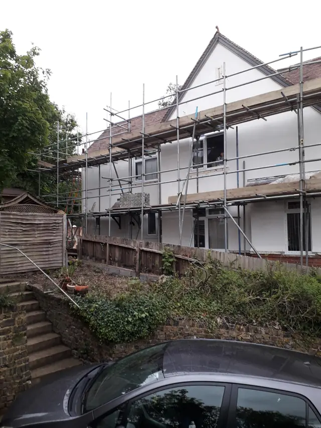 Detached house in Bourne End under scaffolding while its outside walls are plastered